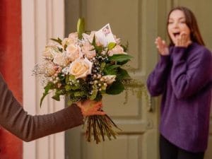 ragazza stupita di fronte a un bouquet di rose rosa