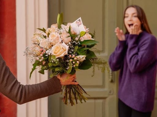 ragazza stupita di fronte a un bouquet di rose rosa