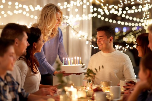 Festa di compleanno con ragazzo festeggiato al centro e persone felici attorno