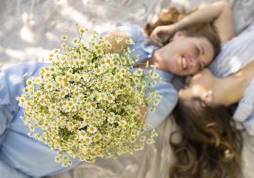 prima-festa-mamma Donna sdraiata accanto a un'altra mentre tiene in mano un grande bouquet di margherite bianche.