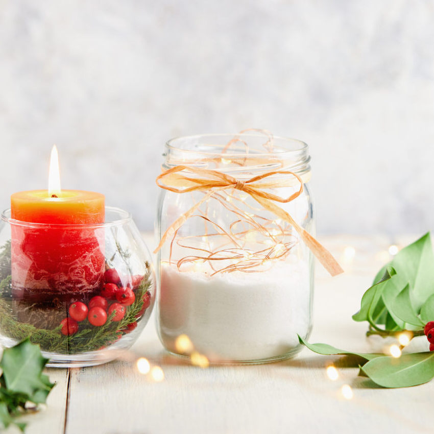 centrotavola di natale con luci in led, barattolo in vetro decorato e barattolo in vetro con una candela rossa al centro